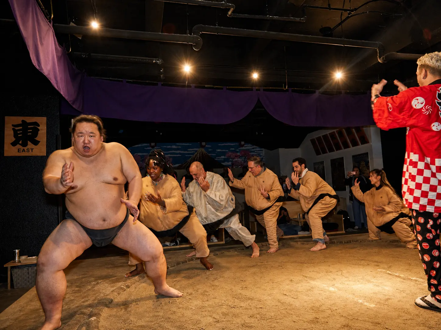 International guests learning fundamental sumo movements with a wrestler